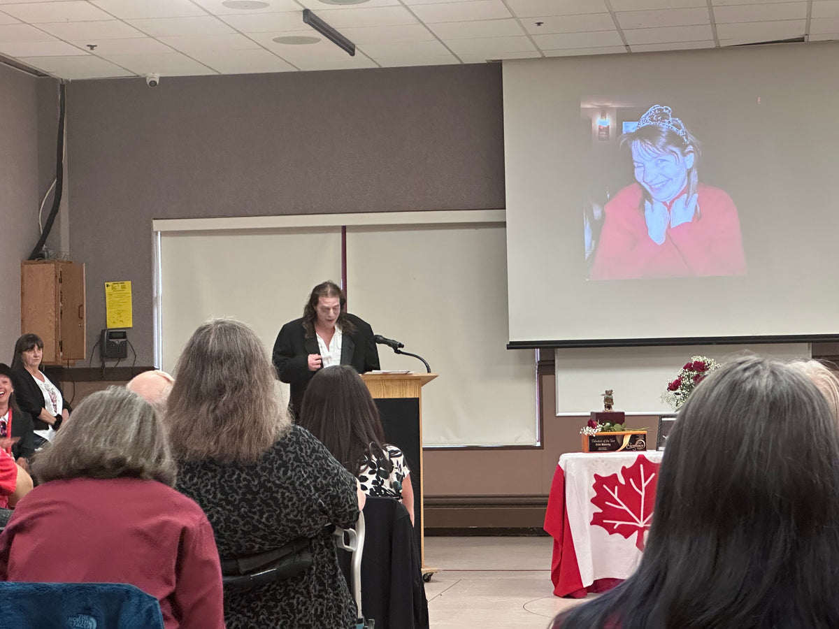 Grizzly Valley Player, Tim Favelle, as Riff Raff, reminices about Erin Wanvig. And image of Erin is projected on the screen behind, while friends and family gather seated in front.